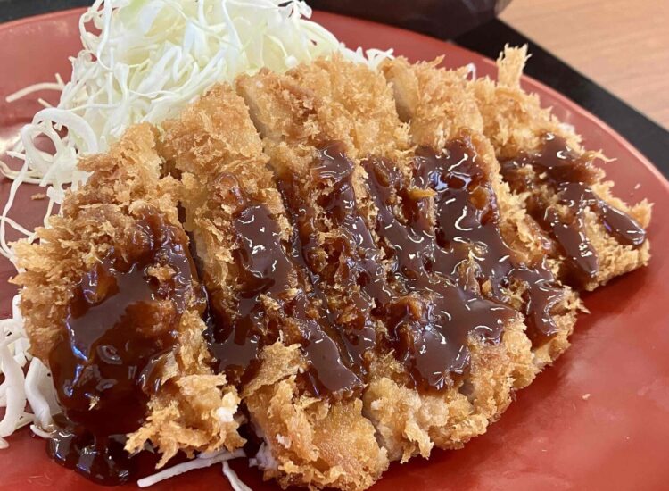 かつやの「ロースカツ定食・ライス大盛」のトンカツにソースをつけたところのアップ